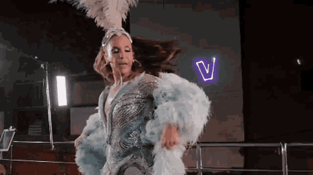 a woman is dancing in front of a neon sign that says v.