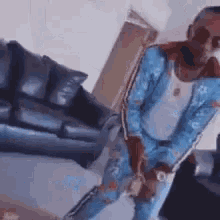 a man in a blue suit is standing in a living room next to a couch .