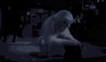 a ghost with long white hair is sitting on the ground in a dark room .