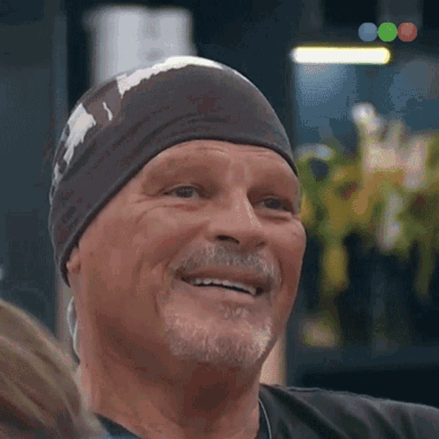 a man with a beard wearing a black headband smiles