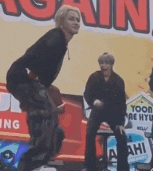 a man is jumping in the air on a stage in front of a sign that says `` yoon ae hyu '' .