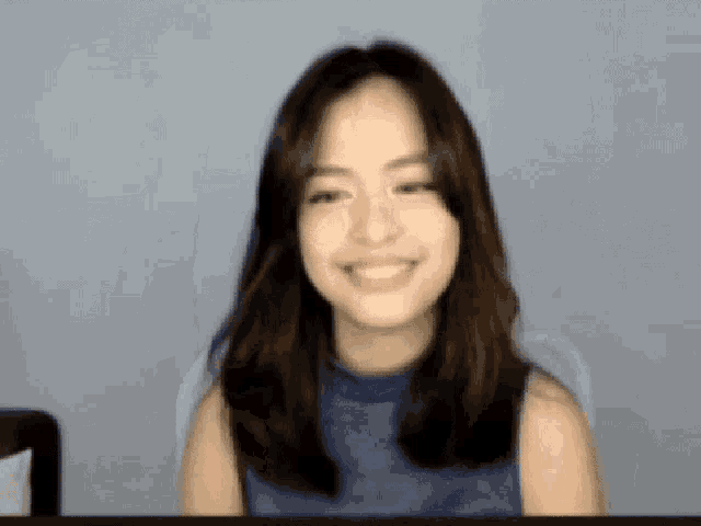 a young woman in a blue shirt is smiling for the camera .