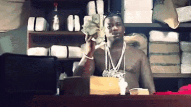 a man without a shirt is holding a pile of money in his hand .