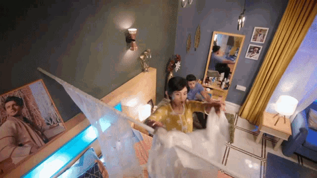 a woman in a yellow dress is holding a white curtain in a bedroom