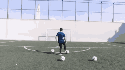 a man in a blue shirt is kicking a soccer ball on a field