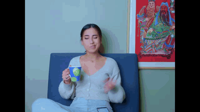a woman sitting on a couch holding a cup of coffee