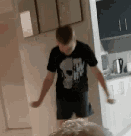 a young boy wearing a black t-shirt with a skull on it is jumping in the air .