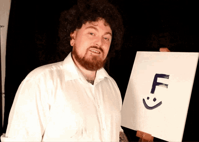 a man in a white shirt is holding a white board with the letter f written on it