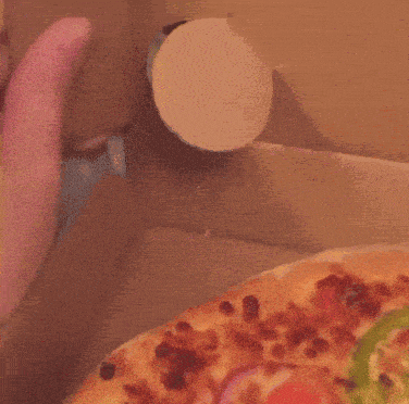 a close up of a person 's hand reaching for a pizza in a box