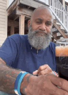 a man with a beard is wearing a blue shirt and has a tattoo on his arm