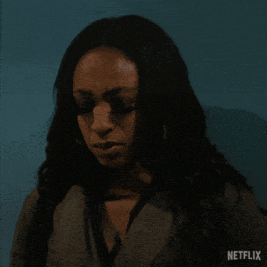 a woman standing in front of a blue wall with a netflix logo on the bottom
