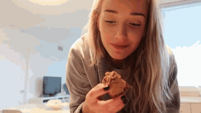 a woman is holding a cookie in her hand and smiling