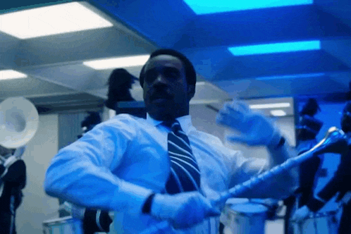 a man in a suit and tie is playing a trumpet in a band