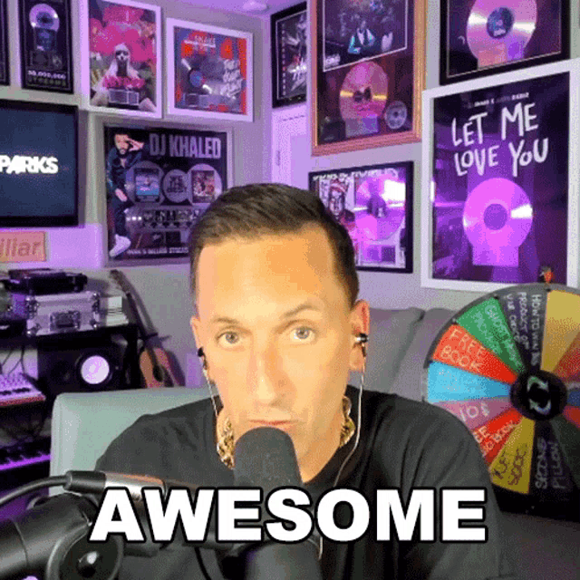 a man sitting in front of a microphone with the words awesome written on his shirt