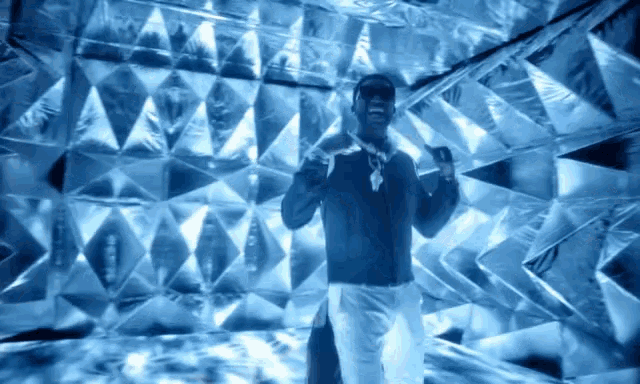 a man in sunglasses stands in front of a shiny wall