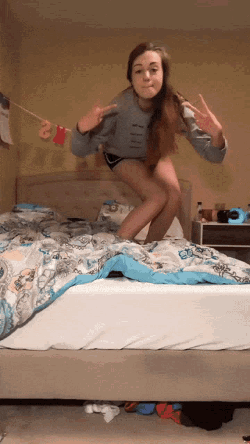 a girl is jumping on a bed with a banner that says 2 on it