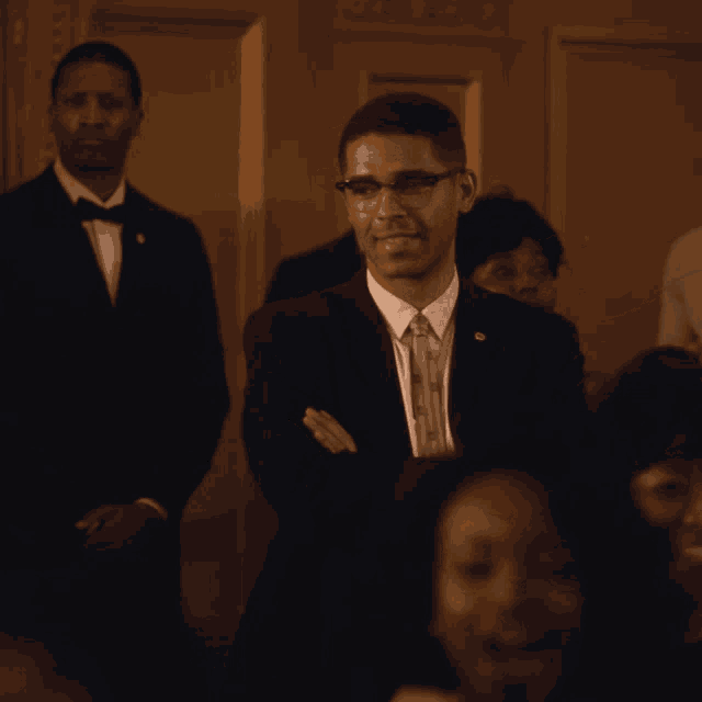 a man in a suit and tie is smiling in a crowd of people