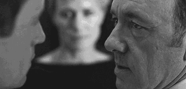 a black and white photo of two men looking at each other in front of a statue .