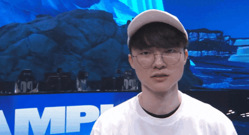 a man wearing glasses and a baseball cap stands in front of a blue wall with the word amp on it