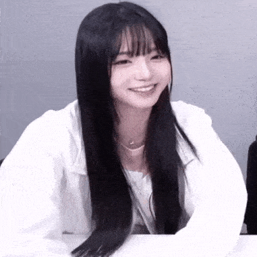 a girl with long black hair and bangs is smiling