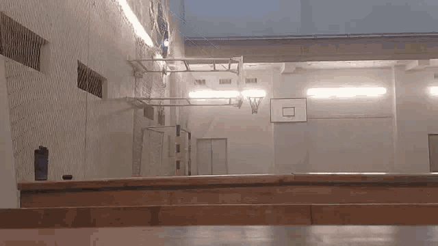 a basketball hoop is hanging from the ceiling of a basketball court .