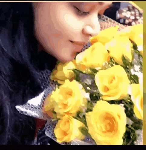 a woman smelling a bunch of yellow roses