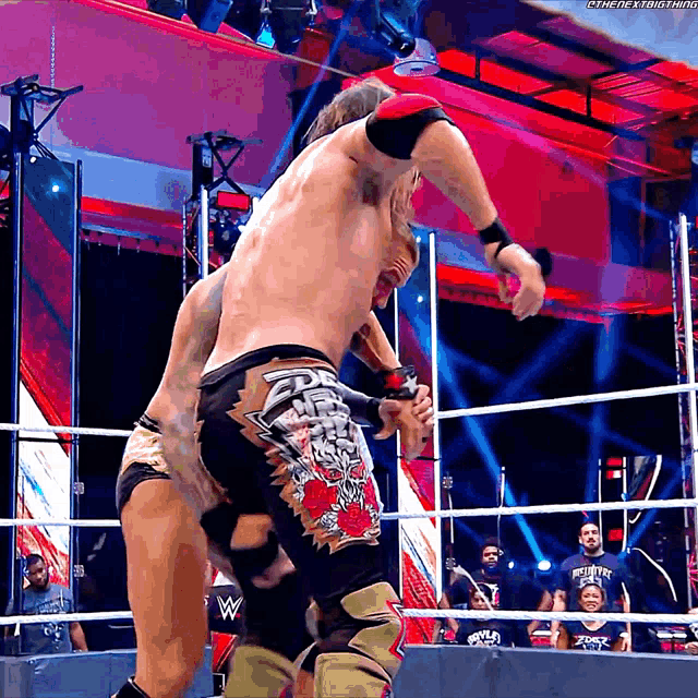 two wrestlers in a wrestling ring with one wearing a pair of shorts with a skull and crossbones design
