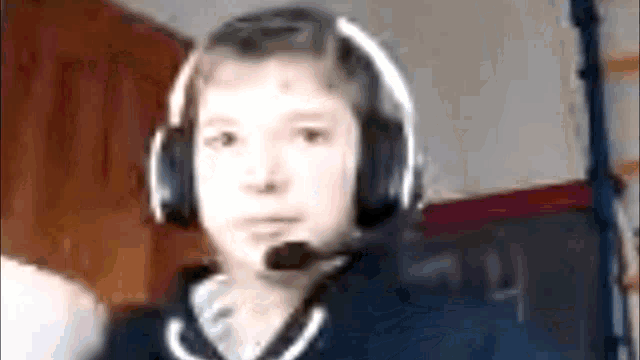a boy wearing headphones and a microphone looks at the camera .
