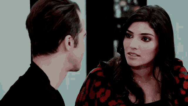 a man and woman are looking at each other and the woman is wearing a necklace