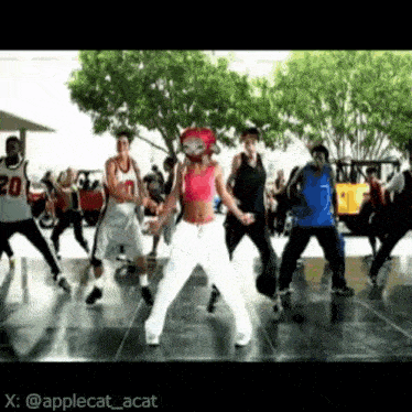 a group of people are dancing on a dance floor with a woman wearing a cat mask .
