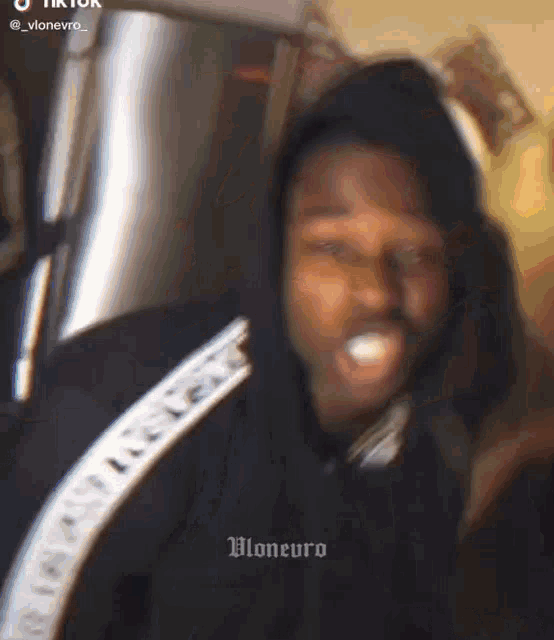 a man in a black hoodie is making a funny face while looking at the camera .