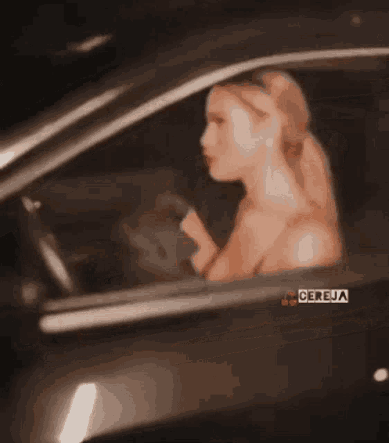 a woman is sitting in a car with the word cereja on the side window