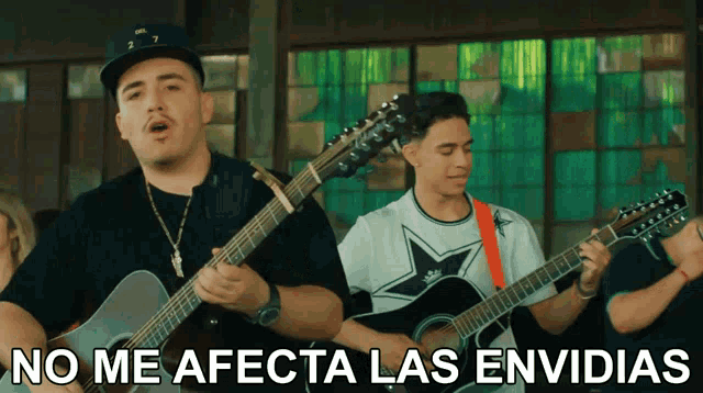 a man playing a guitar next to a sign that says no me afecta las envidias