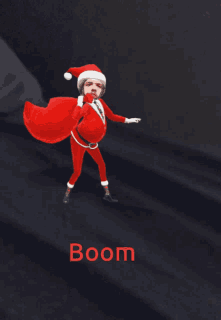 a man in a santa suit is holding a red bag and the word boom is on the bottom right