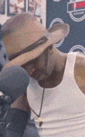 a man wearing a straw hat and a white tank top looks down
