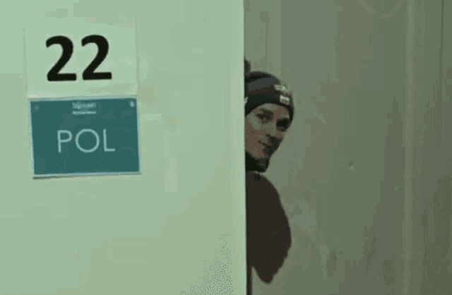 a man peeking out from behind a door with a sign that says pol