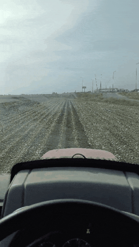 a tractor is driving down a dirt road with a sign in the background that says ' x '
