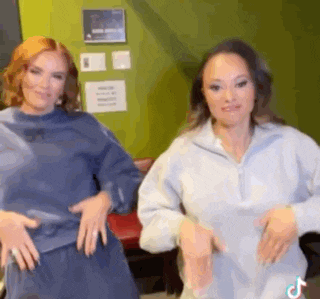 two women are standing next to each other in a room .
