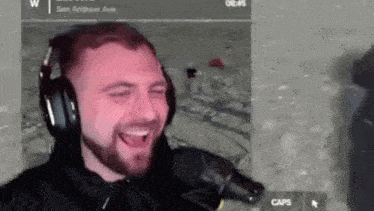 a man wearing headphones is laughing in front of a microphone while playing a video game .