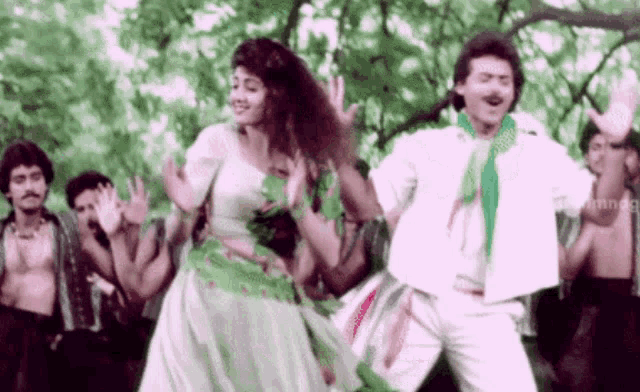 a man and a woman are dancing in front of a crowd of people in a forest .