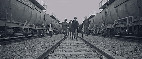 a group of people are walking along train tracks .