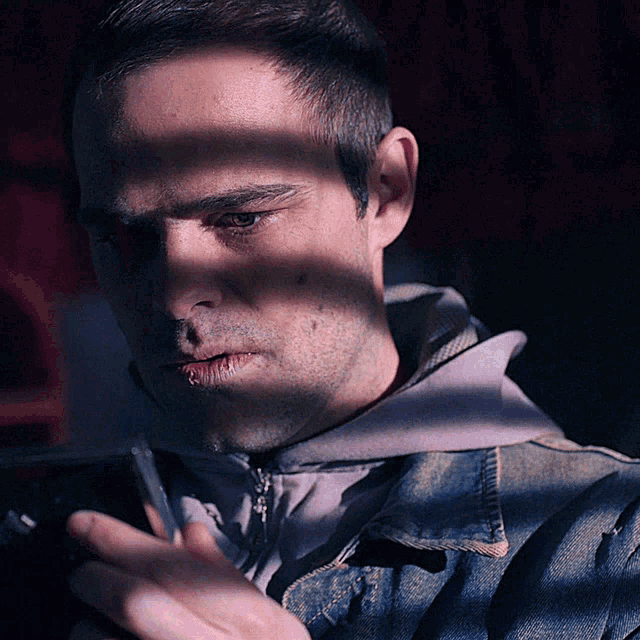 a man wearing a denim jacket is looking at his phone
