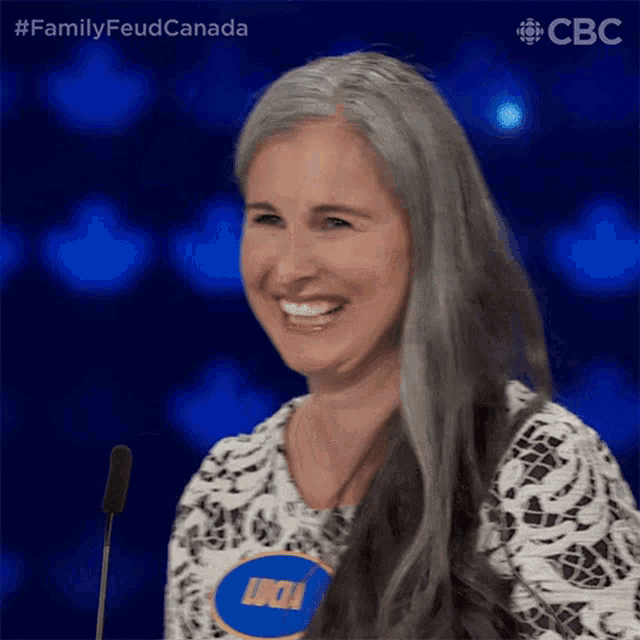 a woman with gray hair is smiling while wearing a name tag that says lucia