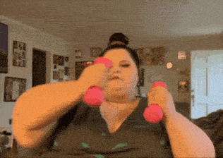 a woman is holding two pink dumbbells in her hands .