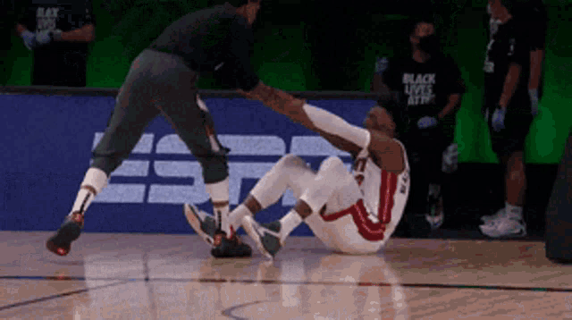 a basketball player has a knee injury and is being helped by a referee