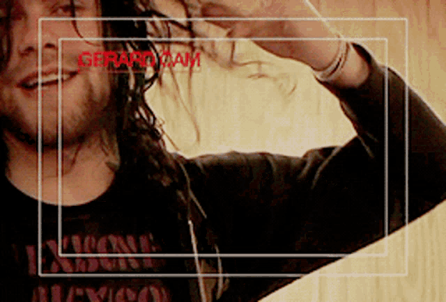 a man with long hair is wearing a black shirt that says ' gerard dam ' on the front