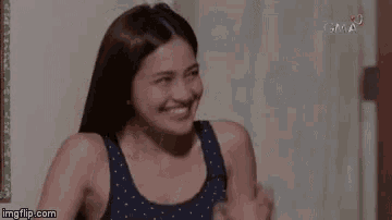 a woman in a blue tank top is smiling while sitting in front of a door .