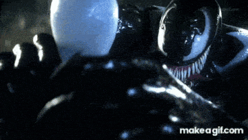venom is holding a light bulb in his hands and looking at it .