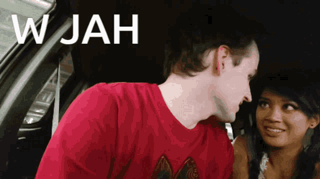 a man in a red shirt is looking at a woman in a car and the word wjah is on the screen