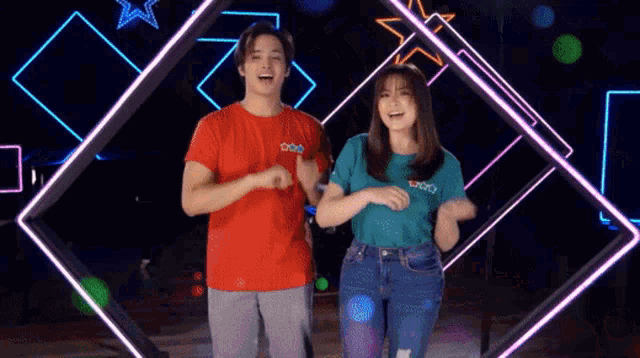 a man and a woman are dancing in front of a neon light display